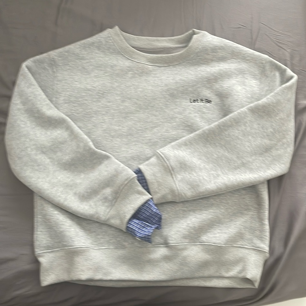 Crew-neck Grey sweater with blue plaid sleeves.
